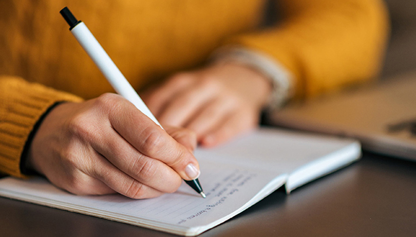 Девушка пишет ручкой в блокноте (фото)